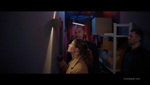 The protagonist looking at a light on the wall in She Sees Red.